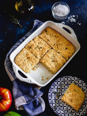 a slice of focaccia served next to the rest of the focaccia