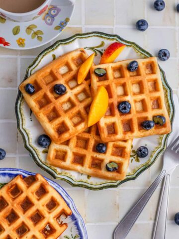 waffles served in plates with fruits and coffee aside