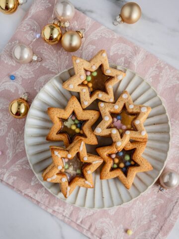 star stained glass cookies on a plate with holiday decoration aside