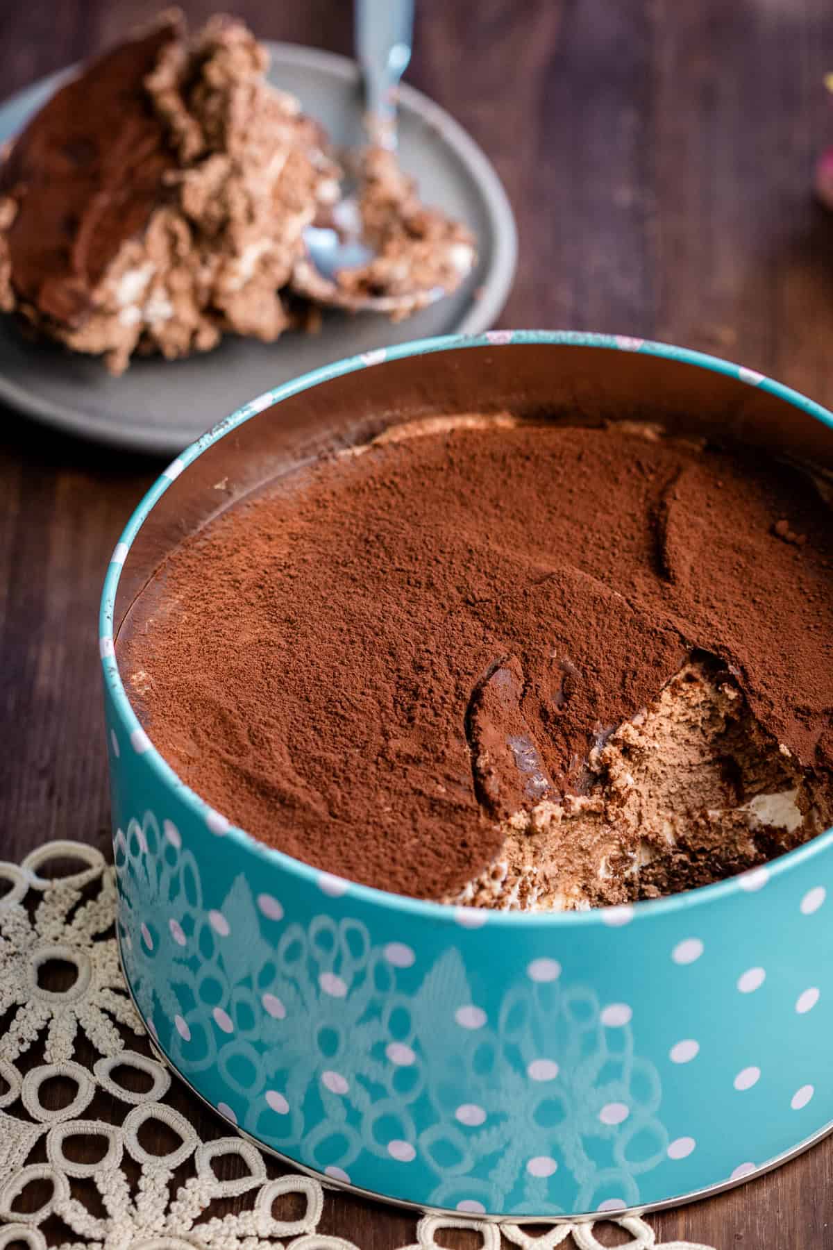 creamy chocolate dream cake in a blue metal tin with a scoop aside